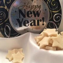 An image of star shaped hypoallergenic chicken dog biscuits laid out on a white cloth with a Happy New Year Sign in the background, encouraging creating healthy options for your dog in the new year.