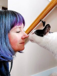 An image showing a pet care specialist bonding with a cat, gently touching noses in a heartwarming moment of connection.