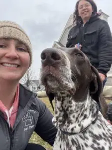 Two pet care specialists guiding a dog through a socialization exercise, emphasizing the importance of continuing to socialize your dog for their overall well-being.