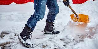 An image depicting a person shoveling snow from a driveway or pathway during winter. The person is dressed in winter clothing, using a shovel to clear the snow. The image represents the importance of finding a snow removal solution for winter vacations.