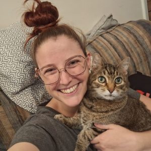 Pet Care Specialist Jacquelynn and her cat, Sundae snuggling up on the couch in Howell, MI.